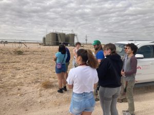 Students standing outside looking at above ground oil tanks from afar